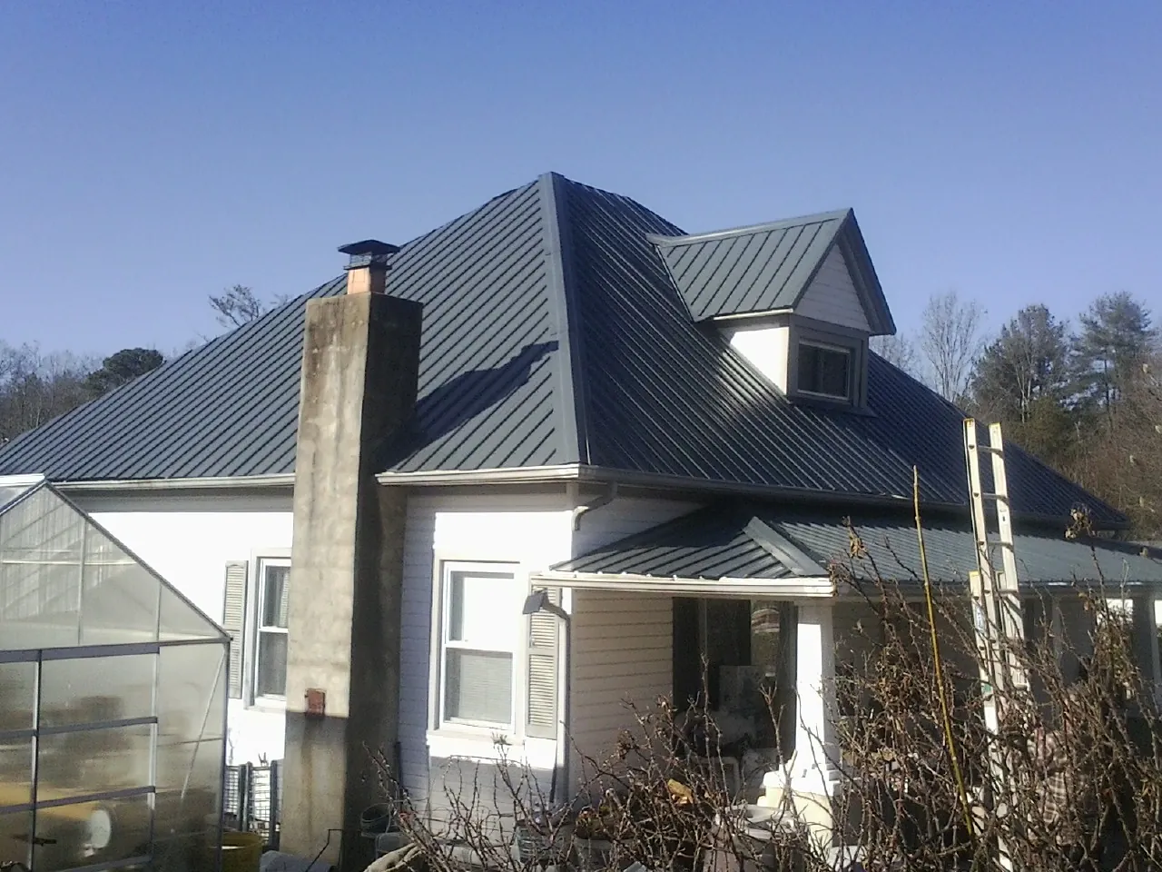 Dark blue standing seam metal roof on a white farmhouse with dormer — Slate & Tile Roof Repair by Roofing Brothers in Mica