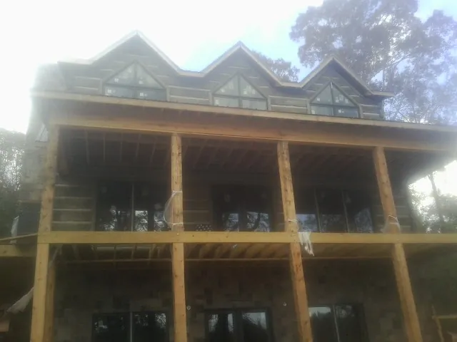 Dormers and porch framing on a large log home under construction — Roof Coating work by our crew in Mica