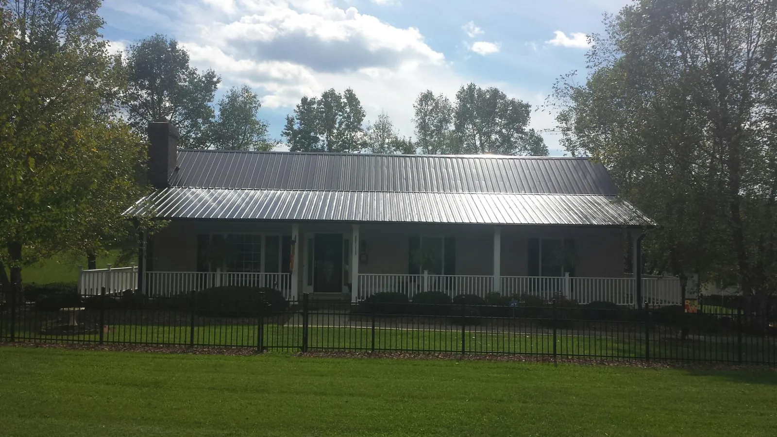 Gray metal roof on a brick ranch with a full width front porch — Gutter Guard Installation work by our crew in Mica