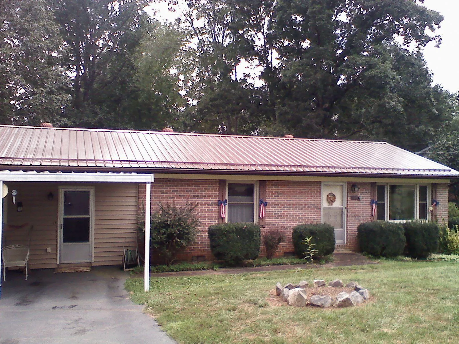 Bronze metal roof and carport on a brick ranch home — Roof Repair work by our crew in Mica