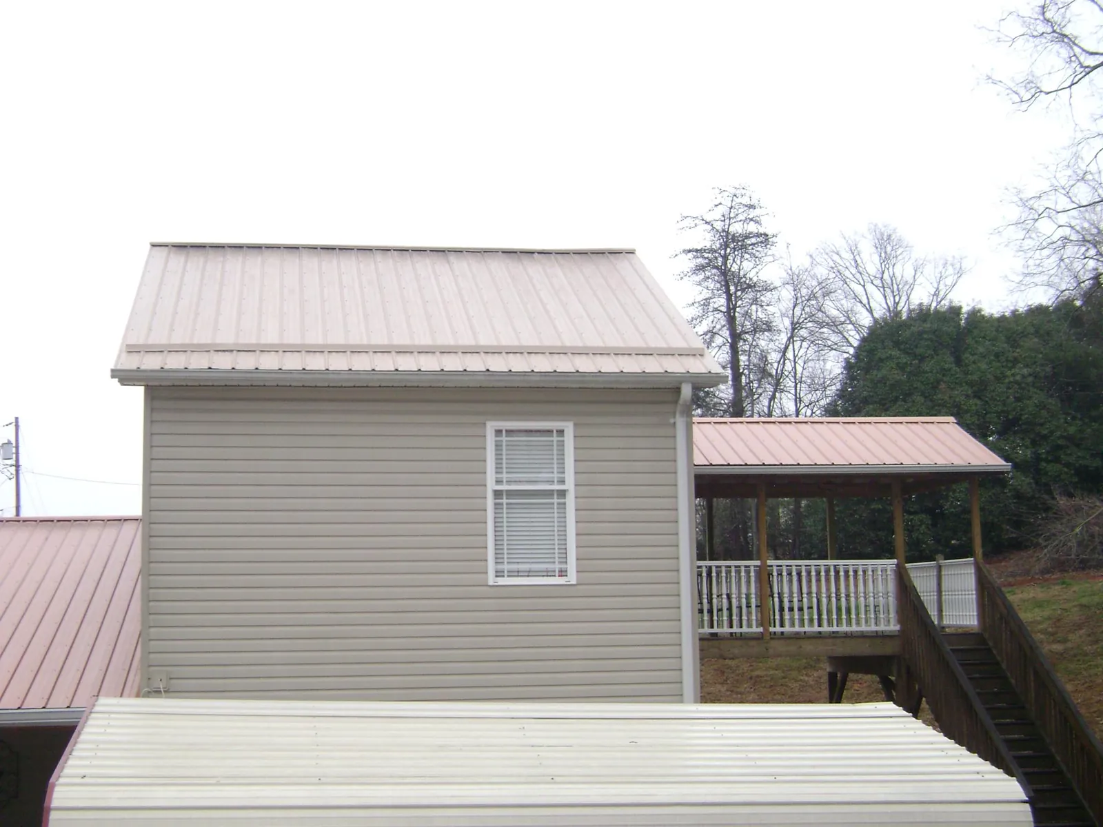 Tan metal roofs on a two story addition and attached porch, from a Roof Replacement job in Mica