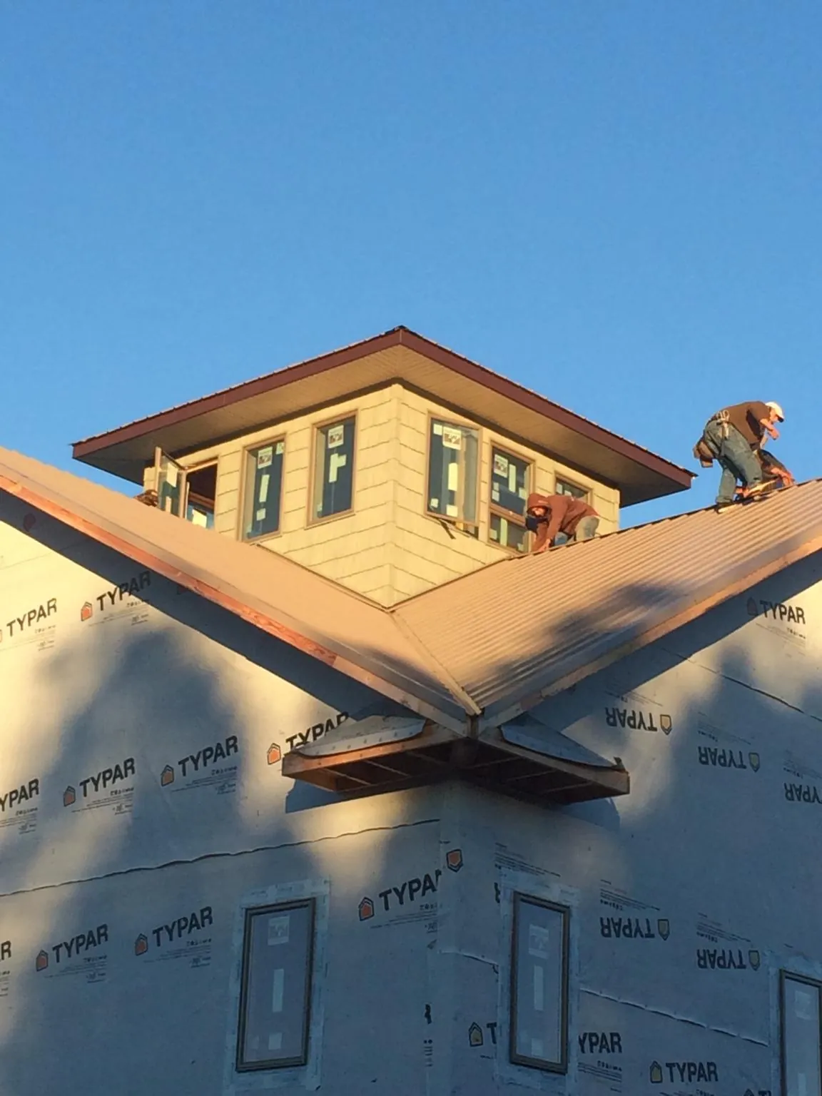 Roofers working around a rooftop cupola on a new metal roof at sunset — Roof Waterproofing in Mica by Roofing Brothers